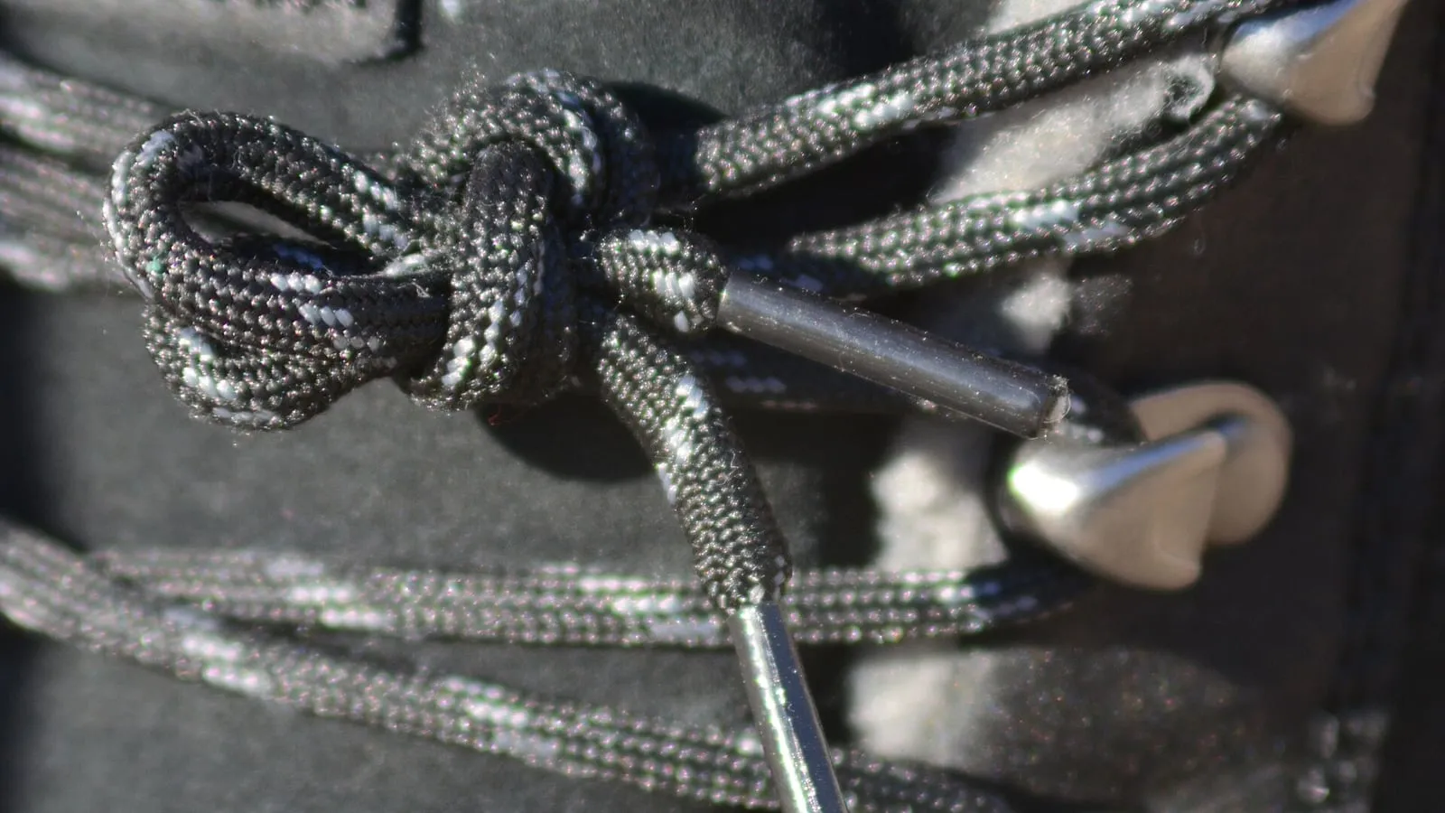 A lace knot on a leather boot, laced through metal eyelets